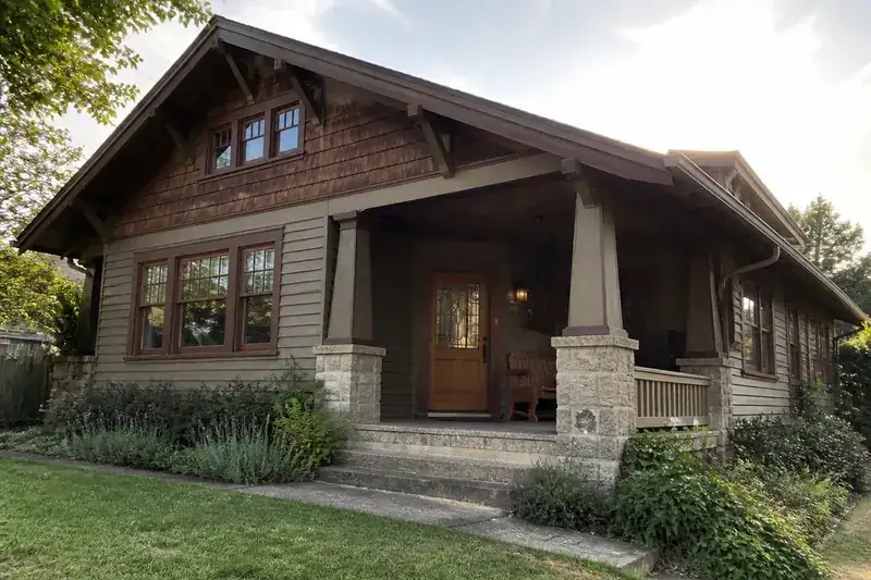 A classic craftsman home with a wide front porch and stone pillars, the kind of house found across Manhattan and Topeka neighborhoods