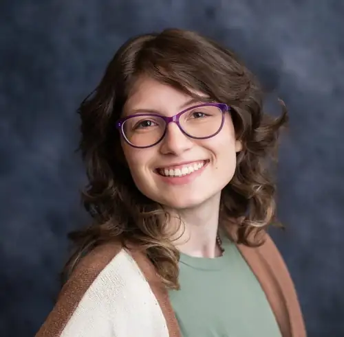 Portrait of Chiara Crisanti — smiling, with brown curly hair and purple glasses