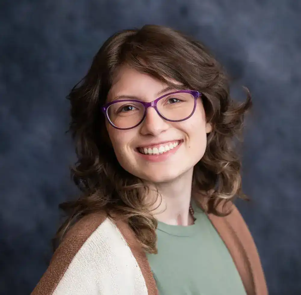 Portrait of Chiara Crisanti — smiling, with brown curly hair and purple glasses